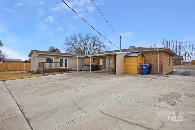 rear view of house with concrete driveway, a patio area, fence, and a wooden deck