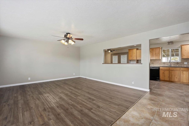 unfurnished living room with a ceiling fan, baseboards, a textured ceiling, and wood finished floors