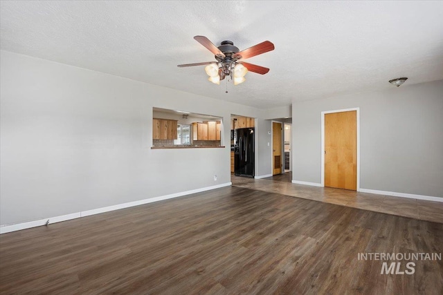 unfurnished living room featuring dark wood-style floors, baseboards, and a textured ceiling