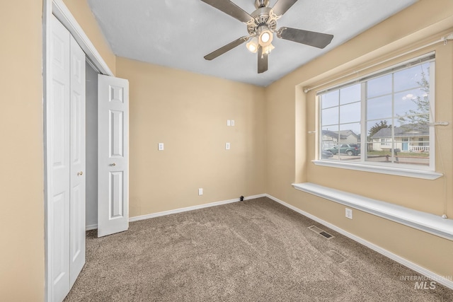 unfurnished bedroom with a closet, baseboards, carpet flooring, visible vents, and ceiling fan