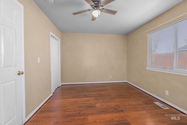 unfurnished room with wood finished floors, baseboards, a ceiling fan, and visible vents