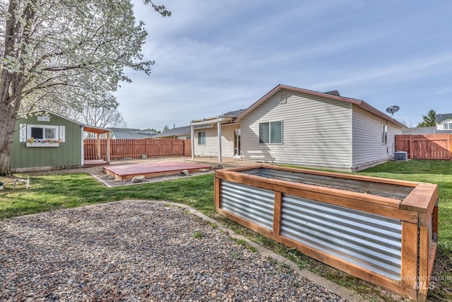 back of property featuring a patio area, a lawn, a fenced backyard, cooling unit, and an outbuilding