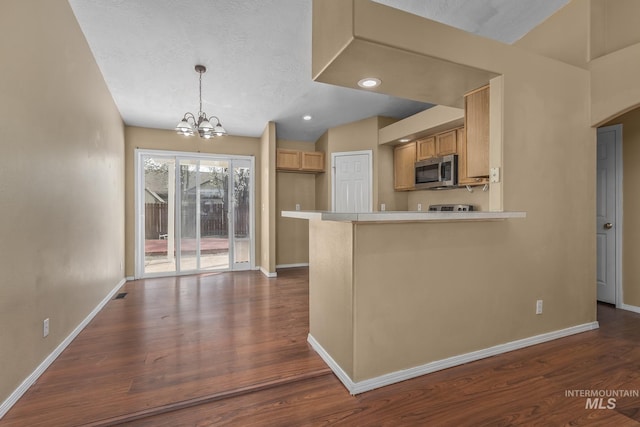 kitchen featuring stainless steel microwave, a notable chandelier, baseboards, a peninsula, and dark wood-type flooring