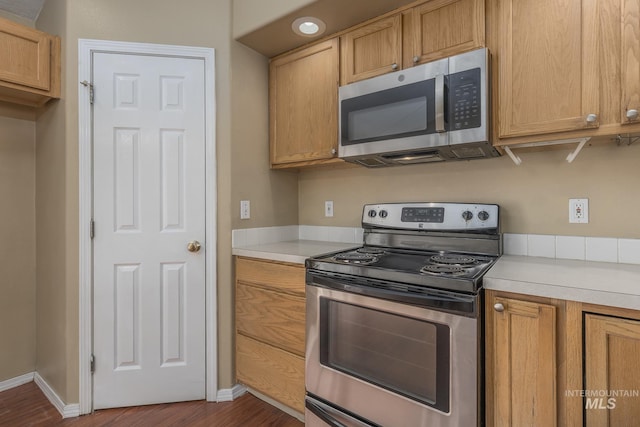 kitchen featuring dark wood-type flooring, light countertops, baseboards, and stainless steel appliances