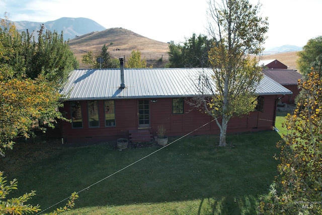 rear view of house with a mountain view and a lawn