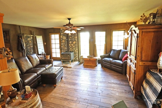 living area with a wood stove, hardwood / wood-style flooring, and a ceiling fan
