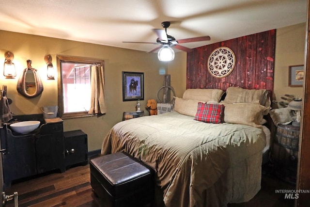 bedroom featuring wood walls, dark wood-type flooring, and ceiling fan