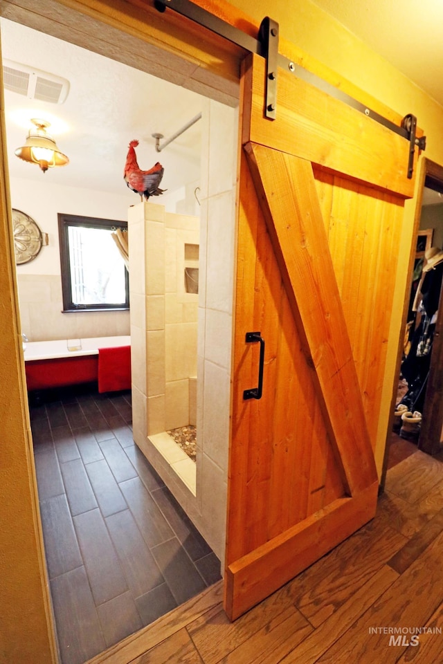 bathroom with tiled shower and wood finished floors