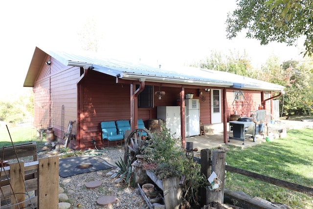 back of property with metal roof, a patio, and a yard