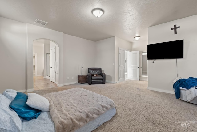 bedroom with arched walkways, baseboards, a textured ceiling, and visible vents