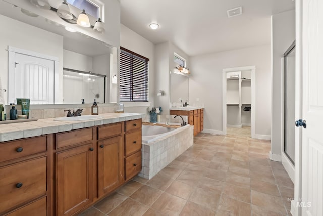 full bathroom with a sink, two vanities, visible vents, a bath, and a stall shower