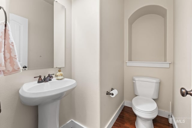bathroom featuring baseboards, a sink, wood finished floors, and toilet