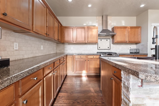 kitchen with dark wood-type flooring, recessed lighting, wall chimney range hood, and tasteful backsplash