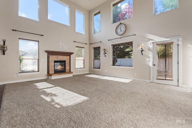 unfurnished living room featuring a high ceiling, baseboards, and carpet