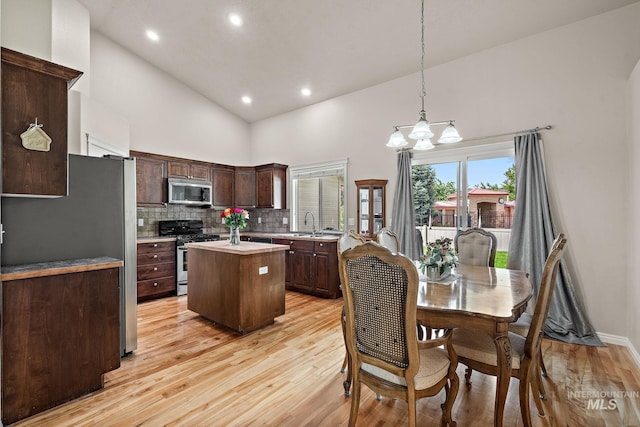 3401 S Murlo Way, Meridian, ID 83642 - kitchen featuring stainless steel appliances, high vaulted ceiling, a kitchen island, light wood finished floors, and dark brown cabinetry