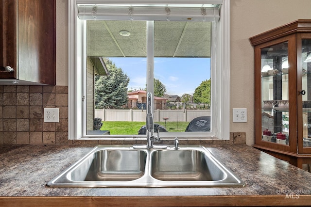3401 S Murlo Way, Meridian, ID 83642 - kitchen view of a sink, dark countertops, tasteful backsplash, glass insert cabinets, and a textured wall