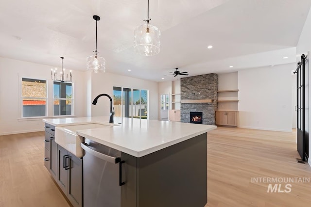 kitchen featuring decorative light fixtures, a fireplace, dishwasher, and an island with sink