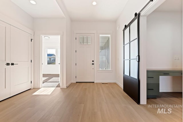 entryway with a barn door and light hardwood / wood-style flooring