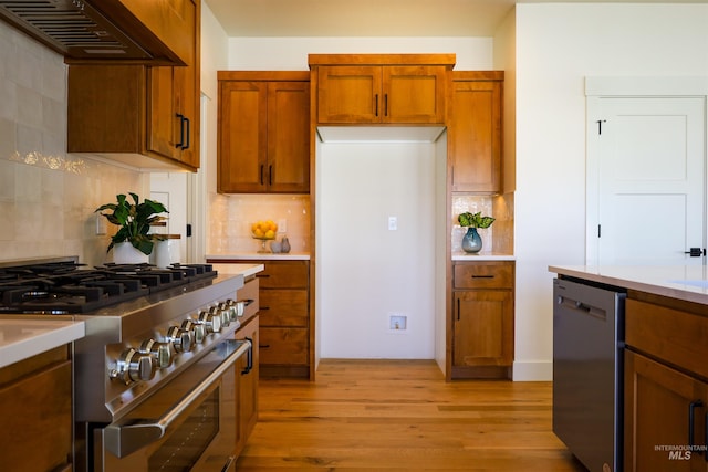 1038 E Fleetwood Ct, Boise, ID 83706 - kitchen featuring light wood-style floors, exhaust hood, decorative backsplash, and stainless steel appliances