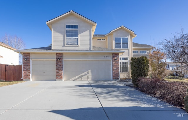 traditional-style home featuring a garage, concrete driveway, brick siding, and fence