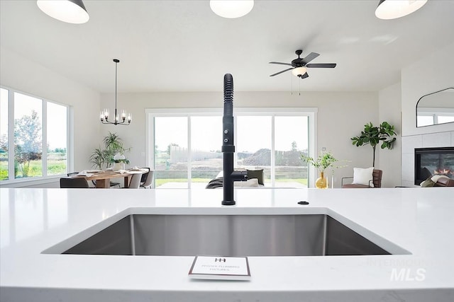 6200 S Binky Ave, Meridian, ID 83642 - kitchen featuring a sink, light countertops, a tiled fireplace, and hanging light fixtures