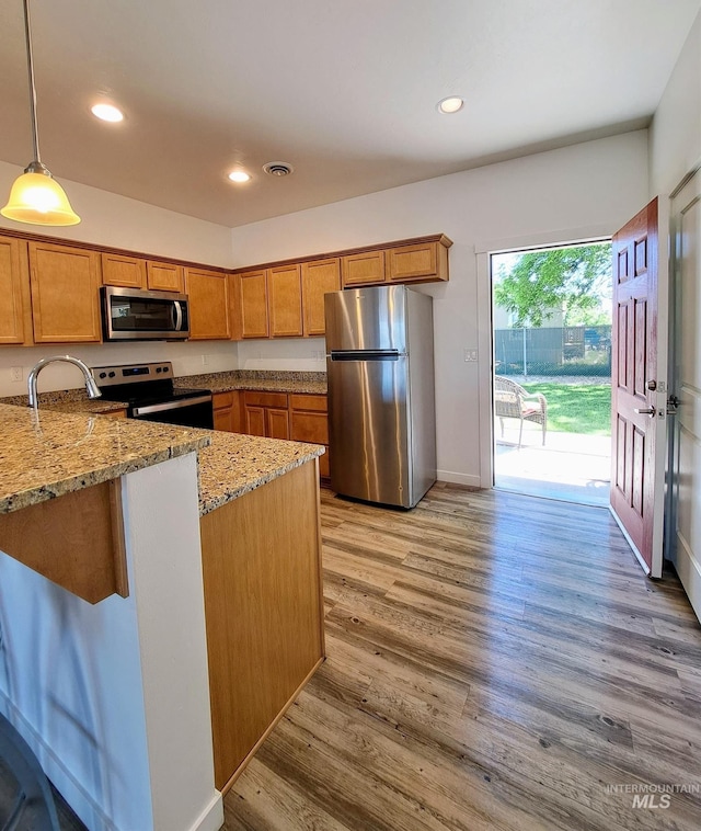 11233 W Gabrielle Dr, Boise, ID 83713 - kitchen with appliances with stainless steel finishes, brown cabinetry, light stone countertops, pendant lighting, and recessed lighting