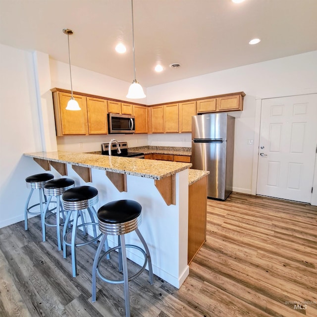 11233 W Gabrielle Dr, Boise, ID 83713 - kitchen featuring appliances with stainless steel finishes, a peninsula, light wood-style floors, light stone counters, and recessed lighting