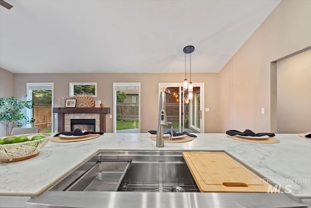 11909 W Patrina Dr, Boise, ID 83713 - kitchen featuring a warm lit fireplace, a sink, decorative light fixtures, open floor plan, and light stone counters