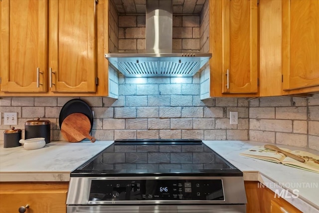 11909 W Patrina Dr, Boise, ID 83713 - kitchen featuring wall chimney range hood, stainless steel electric stove, light countertops, brown cabinetry, and backsplash