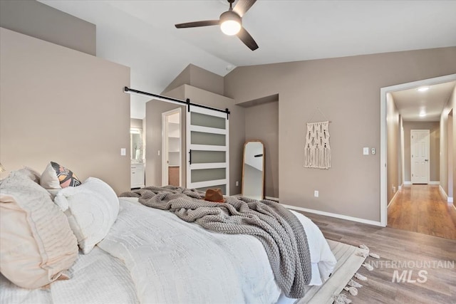 11909 W Patrina Dr, Boise, ID 83713 - bedroom with a barn door, wood finished floors, vaulted ceiling, baseboards, and ceiling fan