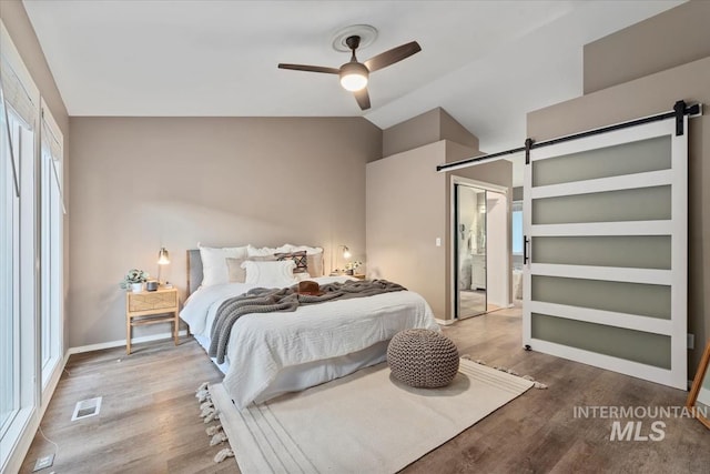 11909 W Patrina Dr, Boise, ID 83713 - bedroom featuring a barn door, wood finished floors, lofted ceiling, baseboards, and ceiling fan