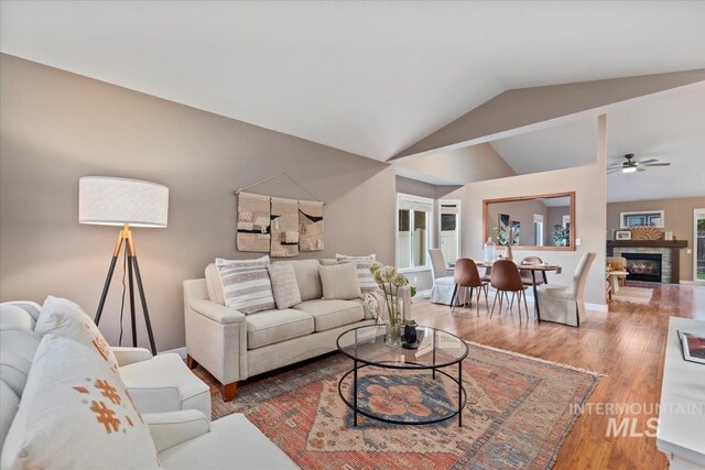 11909 W Patrina Dr, Boise, ID 83713 - living room featuring vaulted ceiling, ceiling fan, wood finished floors, baseboards, and a stone fireplace