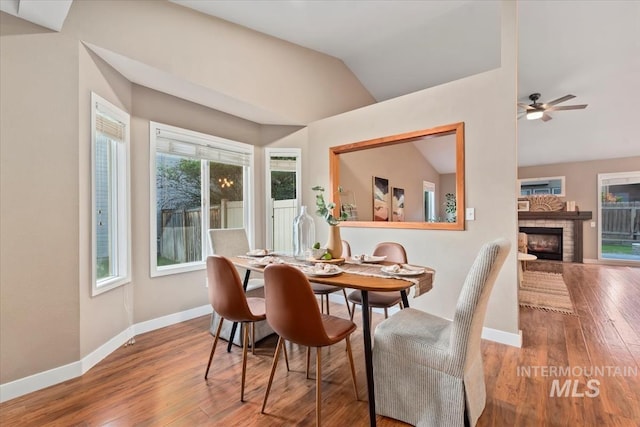 11909 W Patrina Dr, Boise, ID 83713 - dining room featuring lofted ceiling, baseboards, wood finished floors, a fireplace, and a ceiling fan