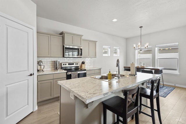 kitchen with decorative backsplash, gray cabinets, stainless steel appliances, light countertops, and a sink