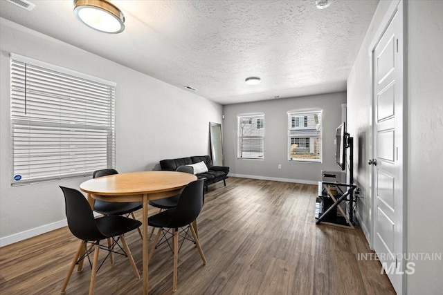 dining space featuring dark wood-style floors, a textured ceiling, visible vents, and baseboards