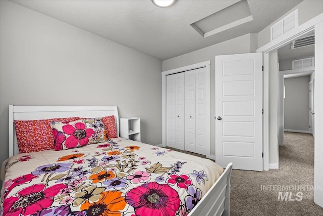 carpeted bedroom with attic access, visible vents, and a closet