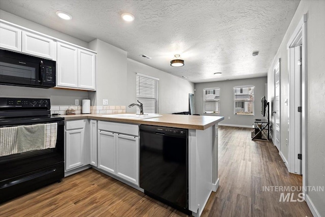 kitchen with open floor plan, white cabinetry, a sink, a peninsula, and black appliances