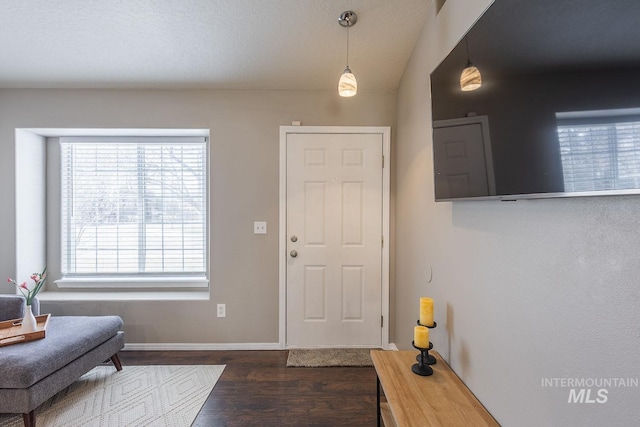 foyer entrance featuring baseboards, wood finished floors, and vaulted ceiling