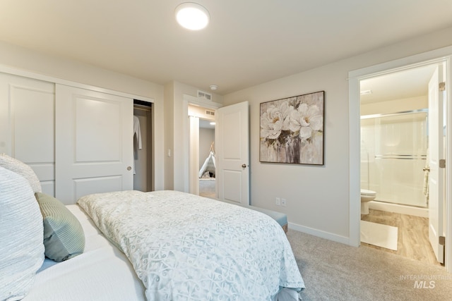 bedroom featuring visible vents, light colored carpet, baseboards, a closet, and ensuite bathroom