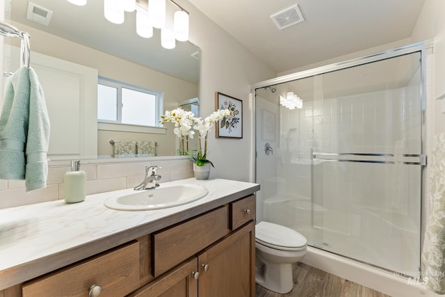 bathroom with visible vents, a stall shower, wood finished floors, and toilet