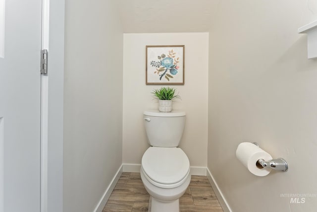 bathroom featuring baseboards, toilet, and wood finished floors