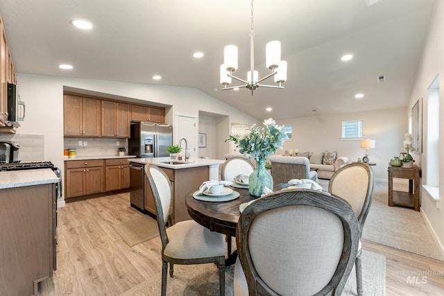 dining space featuring light wood-type flooring, recessed lighting, a notable chandelier, and vaulted ceiling