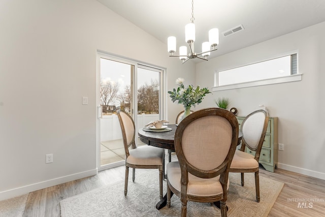 dining room with a chandelier, baseboards, vaulted ceiling, light wood-type flooring, and visible vents