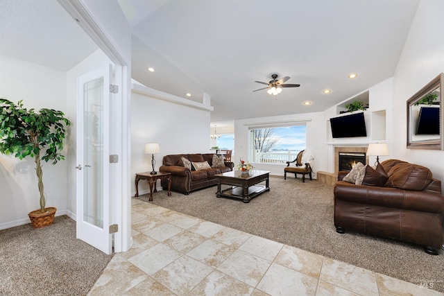 carpeted living room featuring a tile fireplace, vaulted ceiling, and ceiling fan