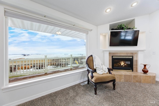 living area with a fireplace, carpet, a water view, and vaulted ceiling