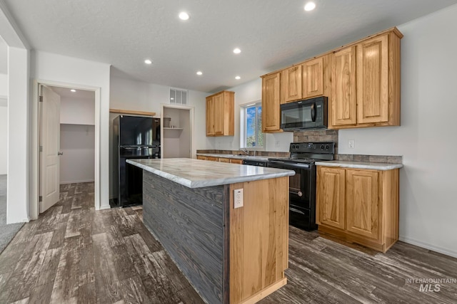 kitchen featuring a textured ceiling, sink, black appliances, dark hardwood / wood-style floors, and a kitchen island