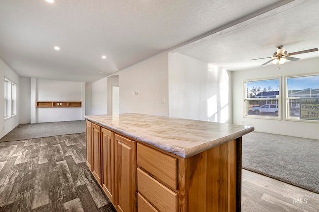 kitchen featuring a textured ceiling, a kitchen island, dark wood-type flooring, and a wealth of natural light