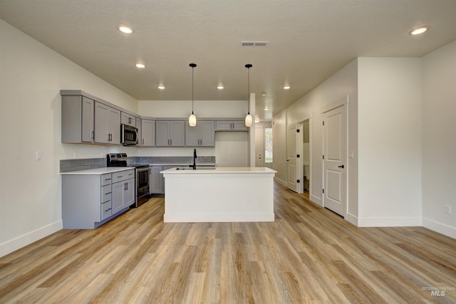 kitchen featuring light wood finished floors, visible vents, gray cabinetry, light countertops, and stainless steel appliances