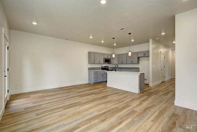 kitchen with visible vents, gray cabinetry, light wood-style floors, stainless steel appliances, and a sink