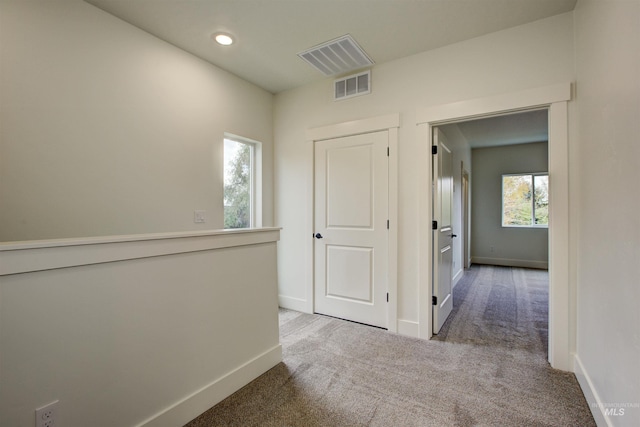 hall with visible vents, carpet floors, and baseboards